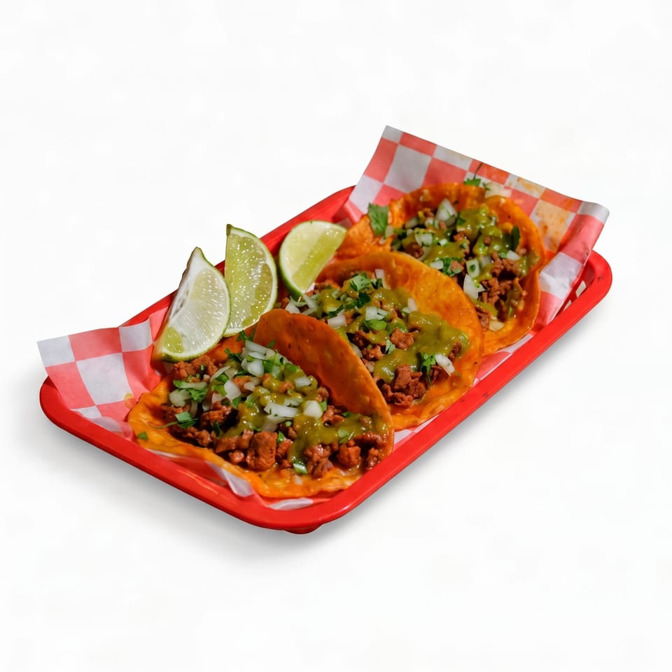 Three crispy beef tacos topped with green salsa, onions, and cilantro in a red tray with lime wedges.